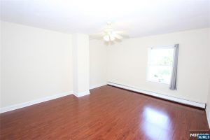 Empty room with cherry floors and two windows